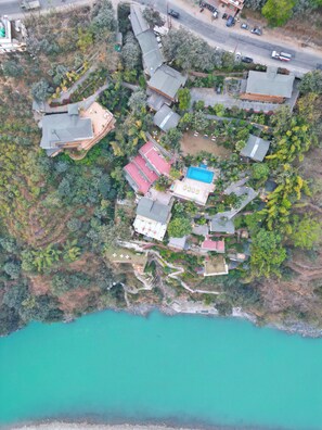 An aerial view of a coastal property with multiple buildings, a swimming pool, and a beach.