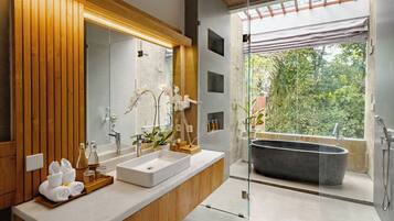 Un baño moderno con tocador de madera, una bañera independiente y un espejo grande.