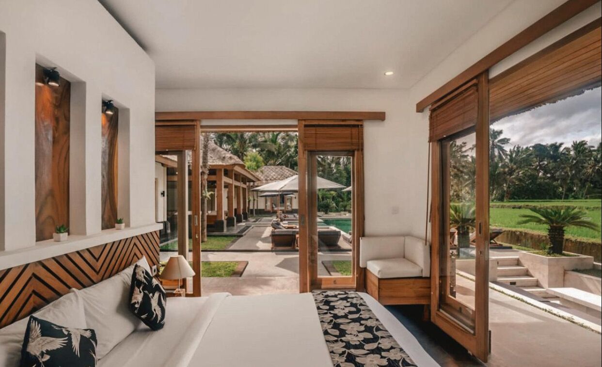 Una habitación de hotel moderna con una cama grande, vistas al área de la piscina exterior y un techo de madera.
