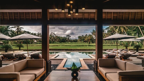 A modern lounge area with a view of a lush garden and a pool. - Villa Jepun (Ubud)