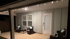 An outdoor patio area with a covered seating arrangement, a door with a window, and a ceiling with recessed lighting.