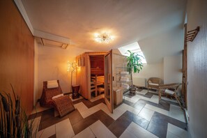 A cozy room with a wooden bench, a small table, a shelf with towels, and a plant. - Komfort Hotel am Kurpark (Bad Homburg v.d. Hoehe)