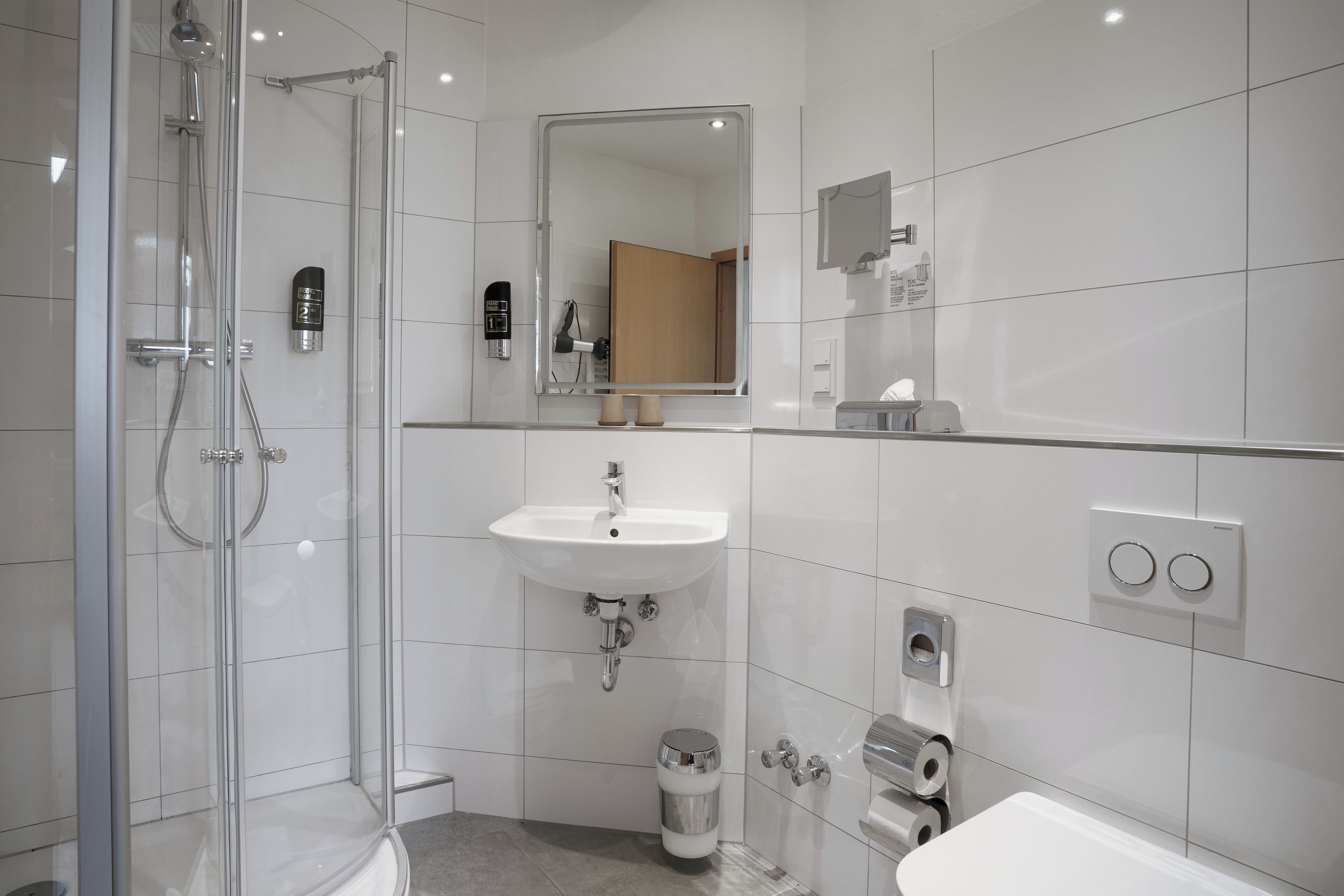 Un baño moderno con cabina de ducha de vidrio, lavamanos blanco y un inodoro.