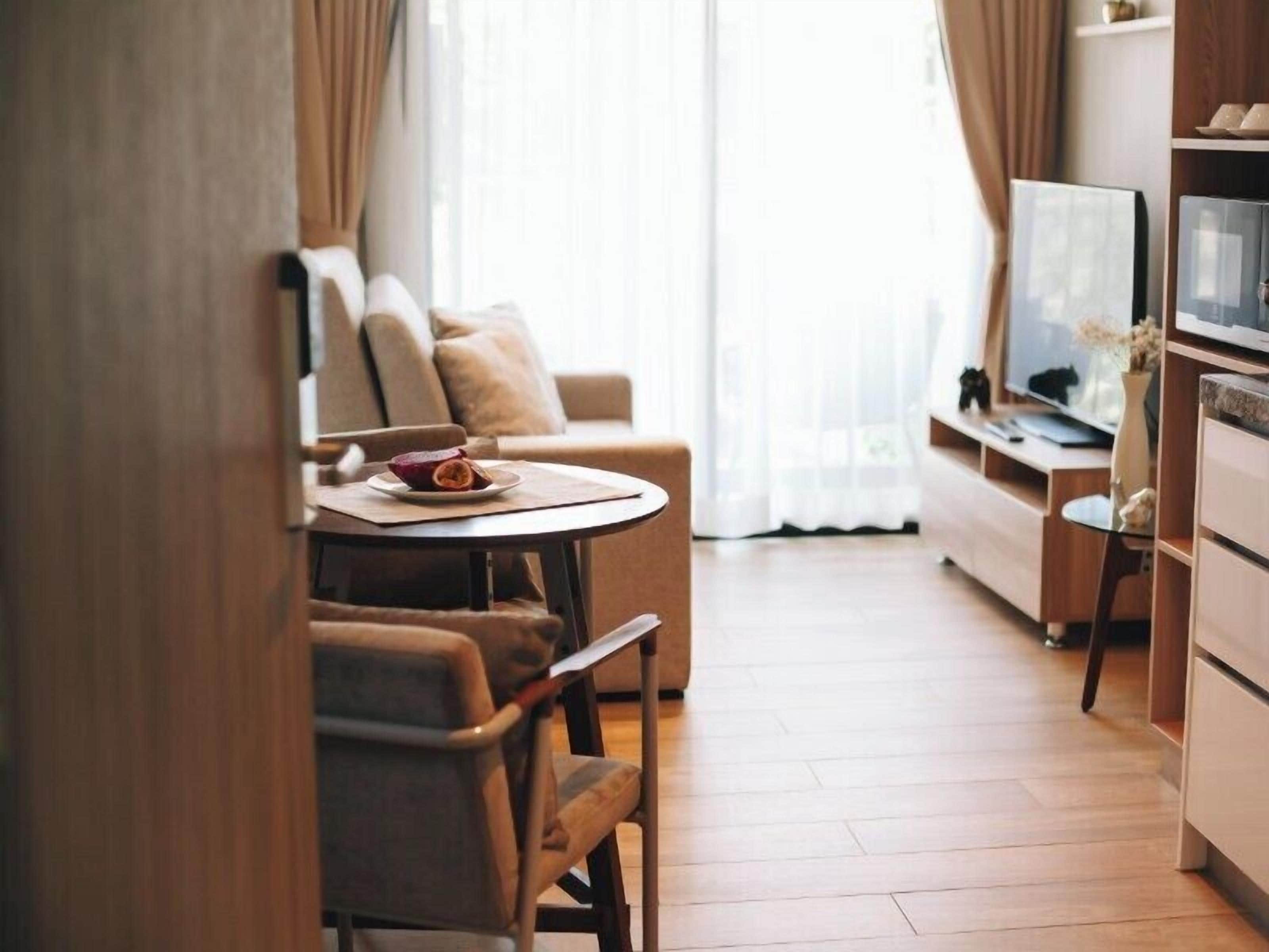 A modern living room with a sofa, a dining table with a plate of food, a TV, and a kitchen area.