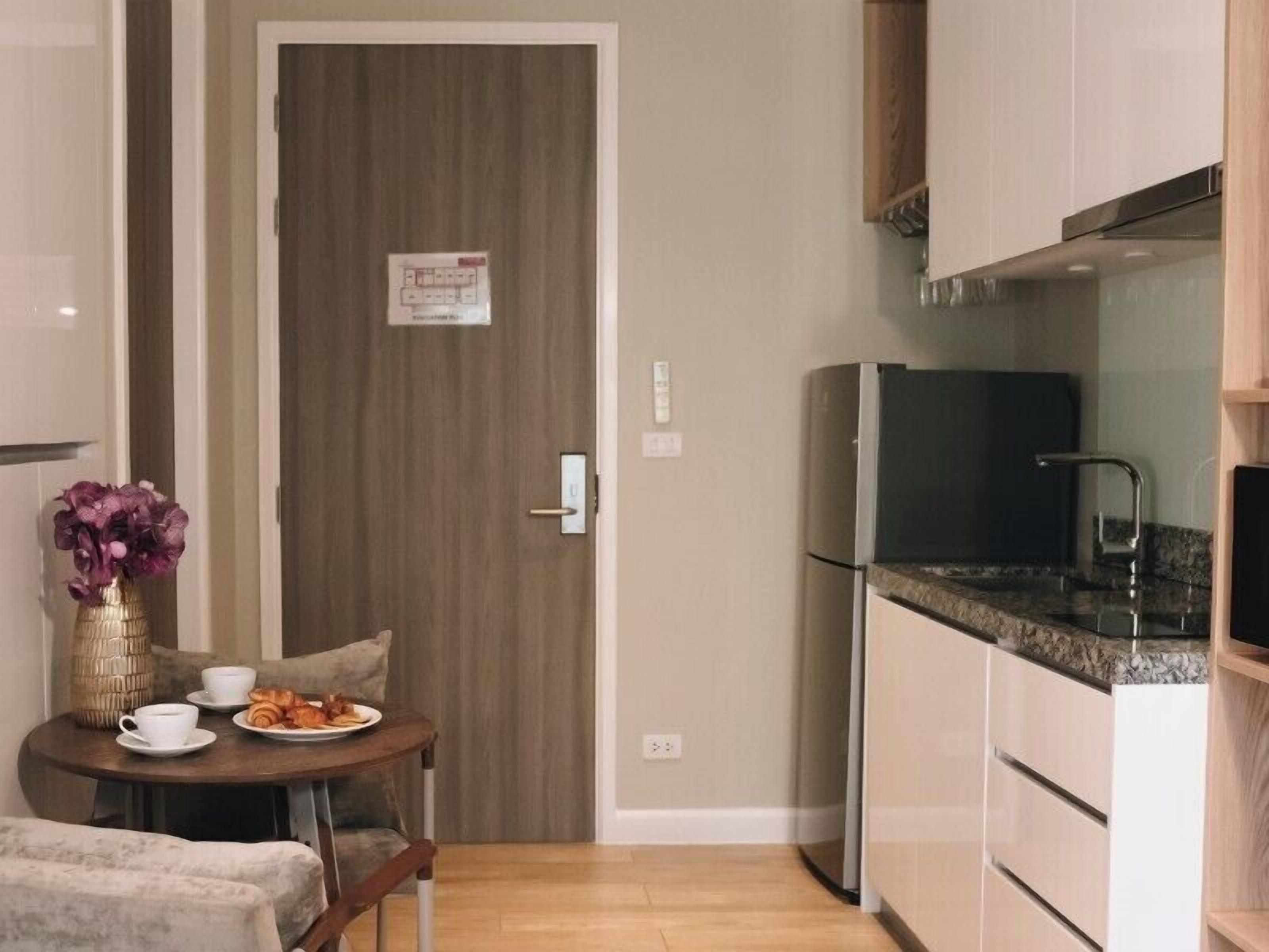Una cocina compacta con refrigerador, un lavamanos y un comedor con una mesa dispuesta para dos.