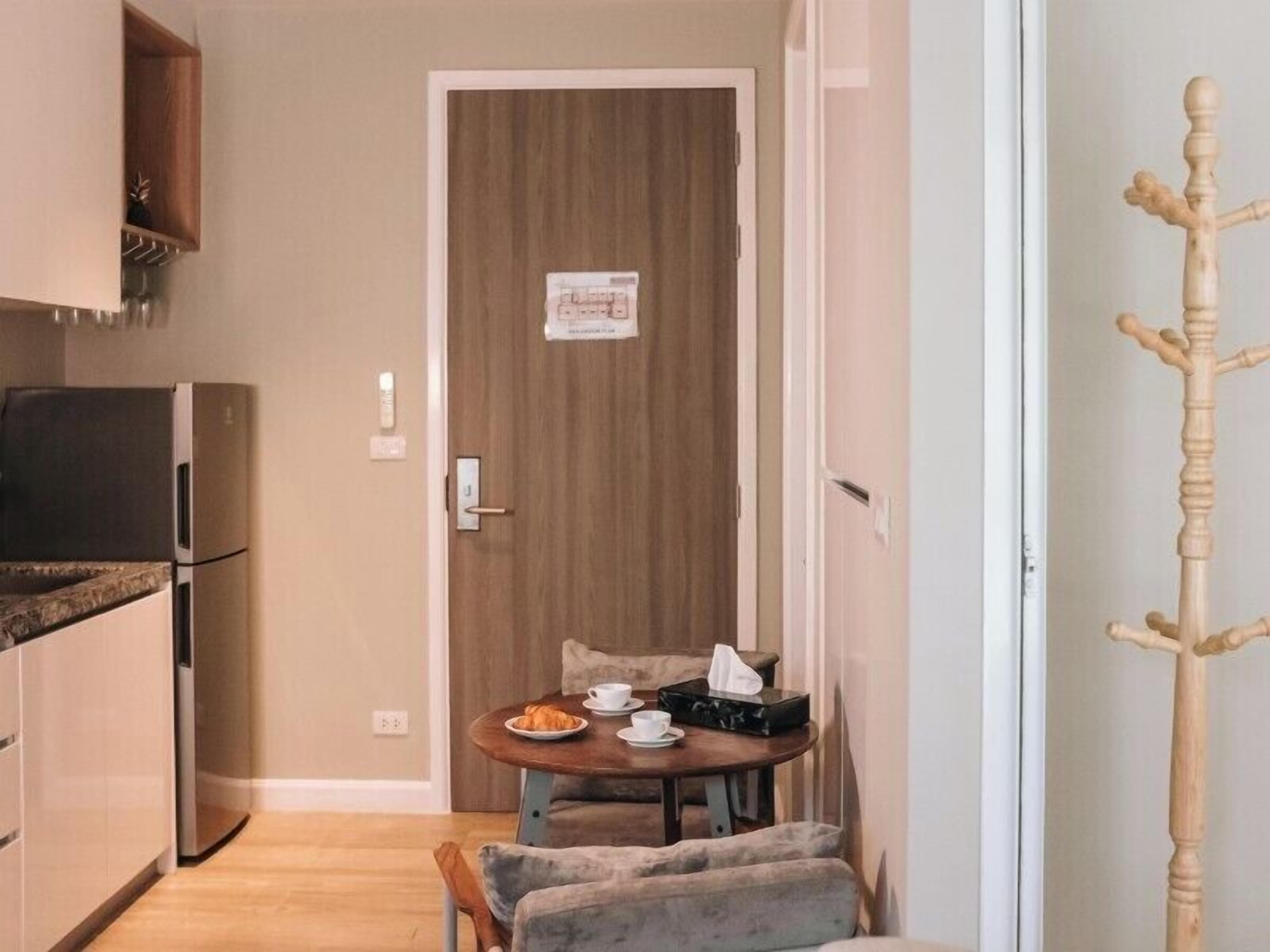 A compact kitchen with a refrigerator, a wooden door, and a small dining area with a table and chairs.
