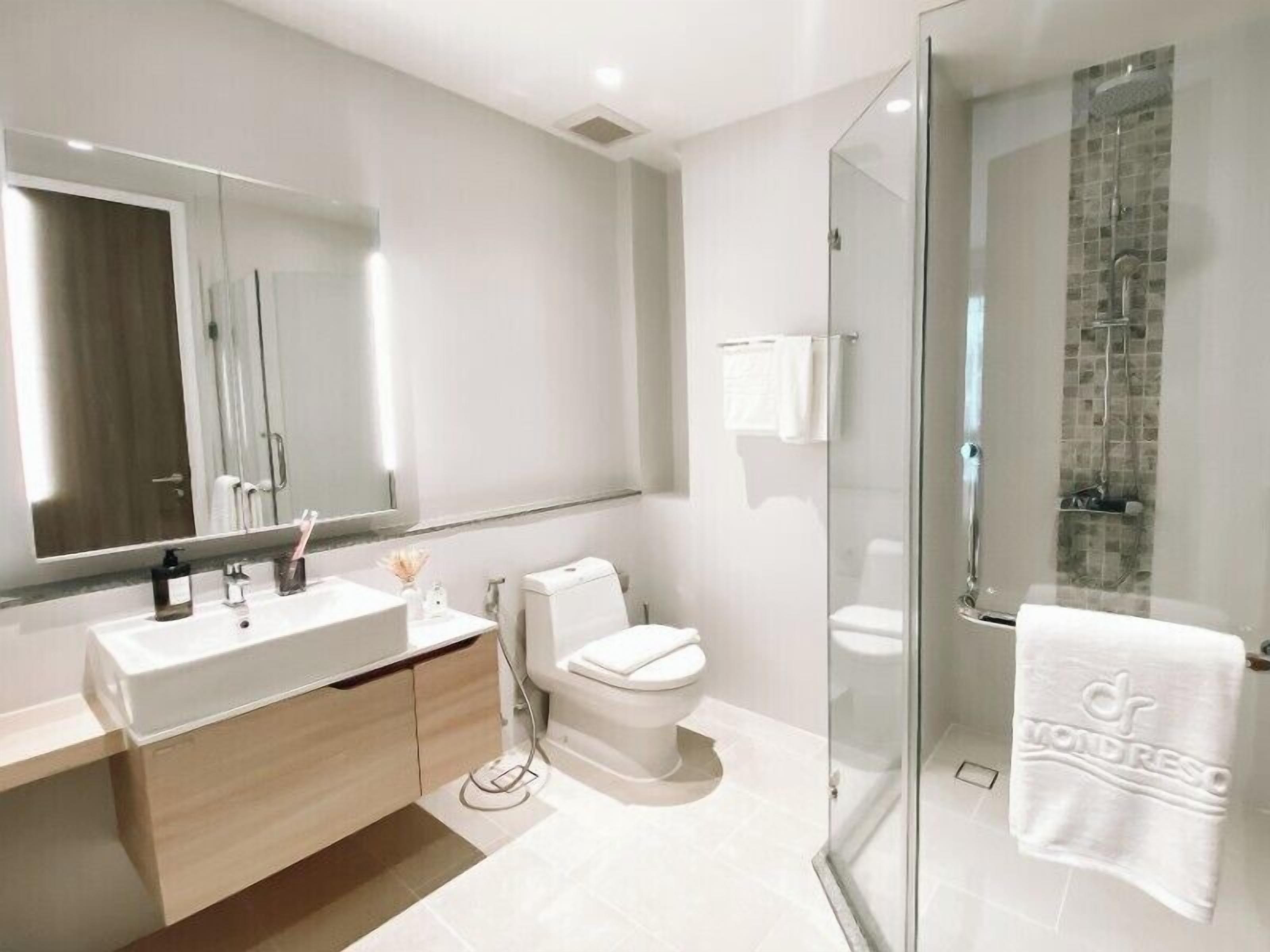 A modern bathroom with a glass-enclosed shower, a white sink, and a toilet.