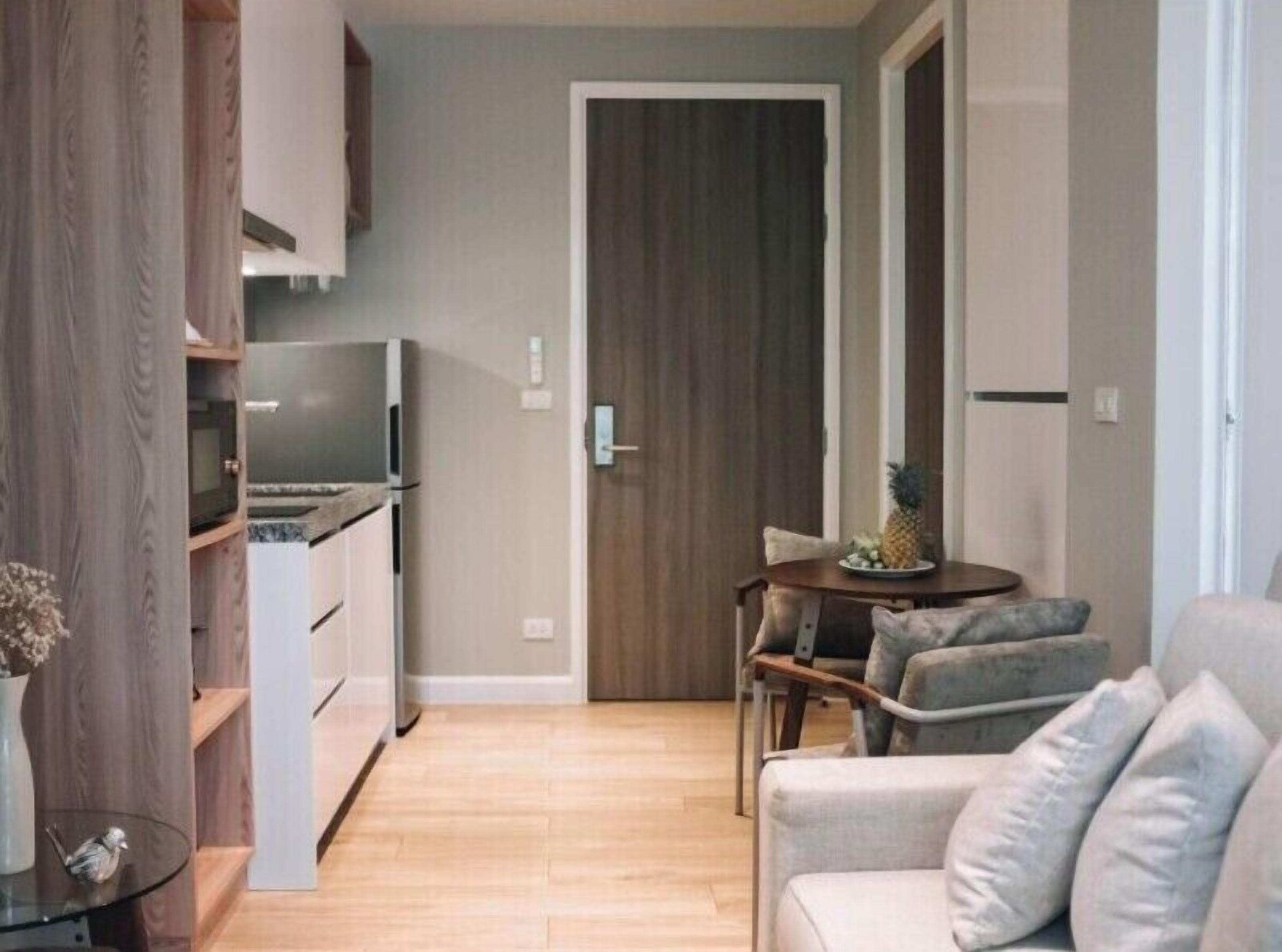 A compact living space with a kitchenette, a dining area with a table and chairs, and a sofa.