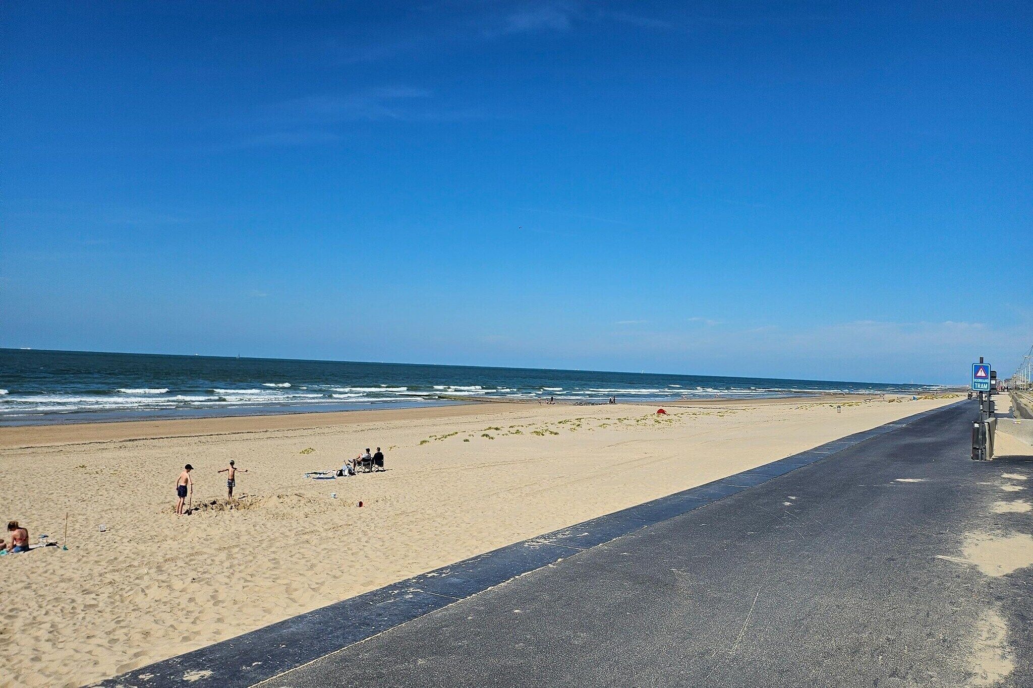 Une plage avec une promenade dallée, un poste de surveillance pour les sauveteurs et l’océan en arrière-plan.