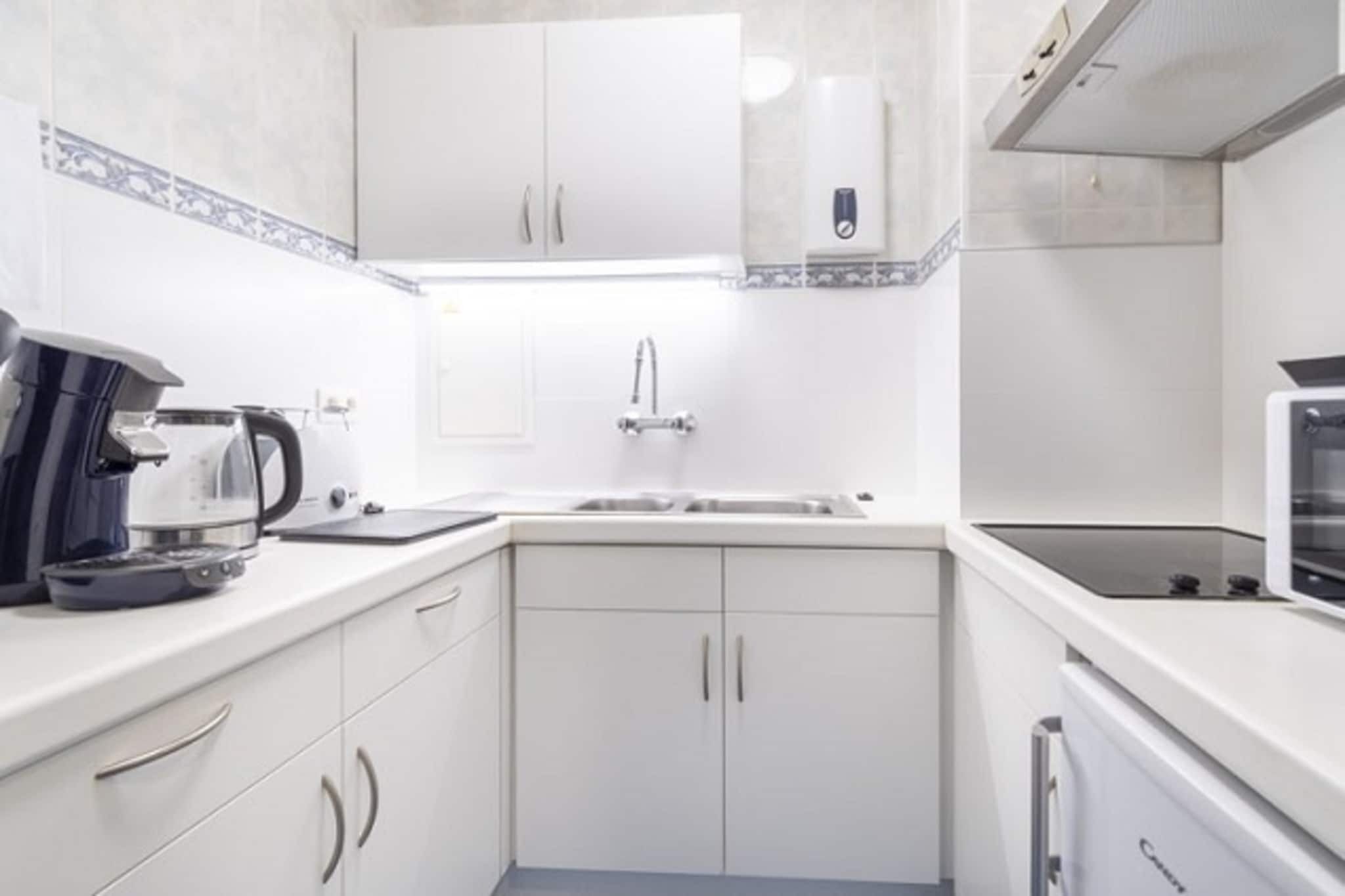 A modern kitchen with white cabinets, a built-in stove, and a coffee maker.
