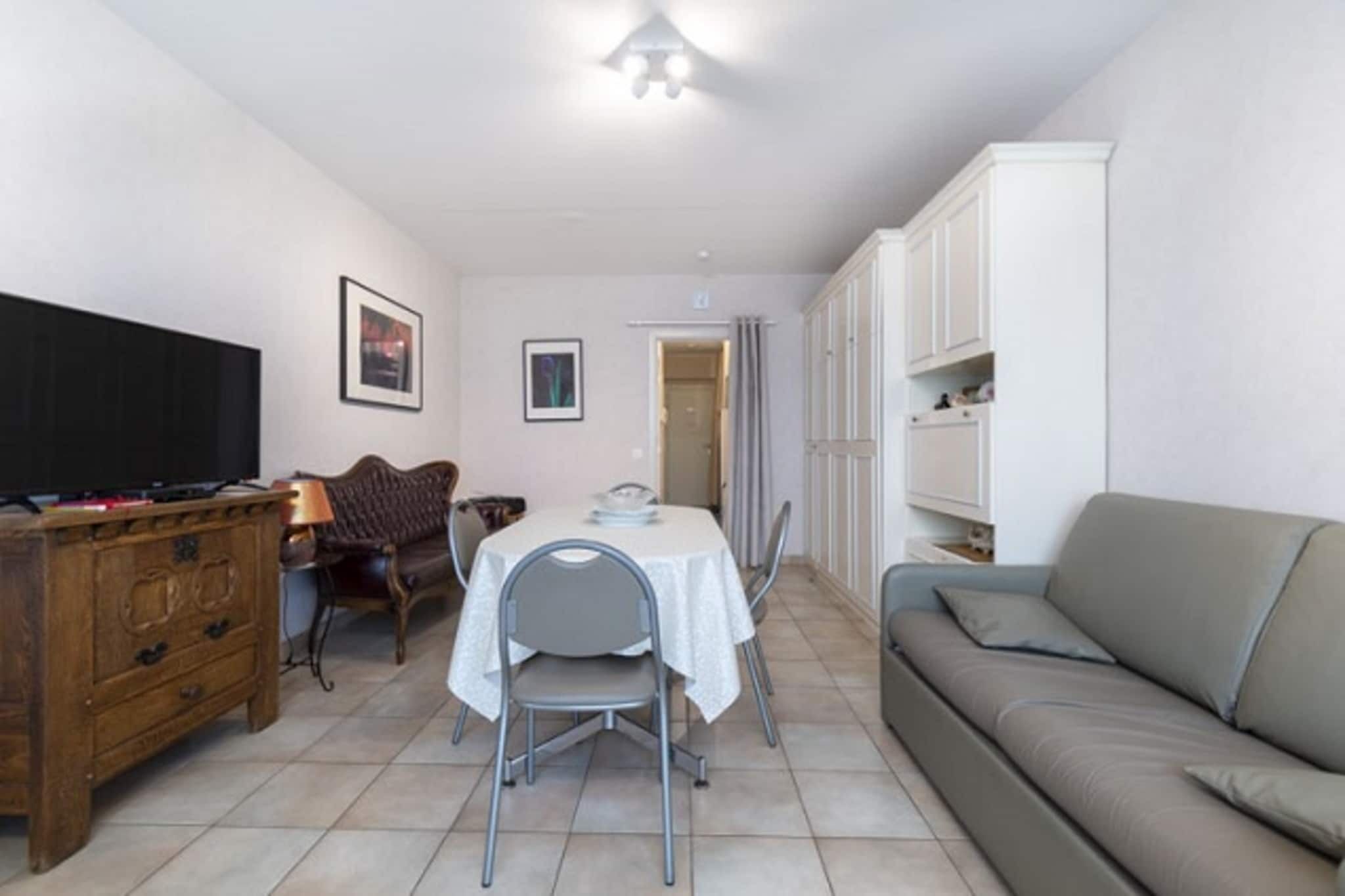 A compact living space with a dining table, chairs, a sofa, a TV, and a cabinet.