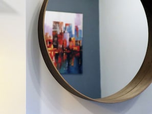 A round mirror with a wooden frame on a wall. - mySTAY BGC East (Makati)