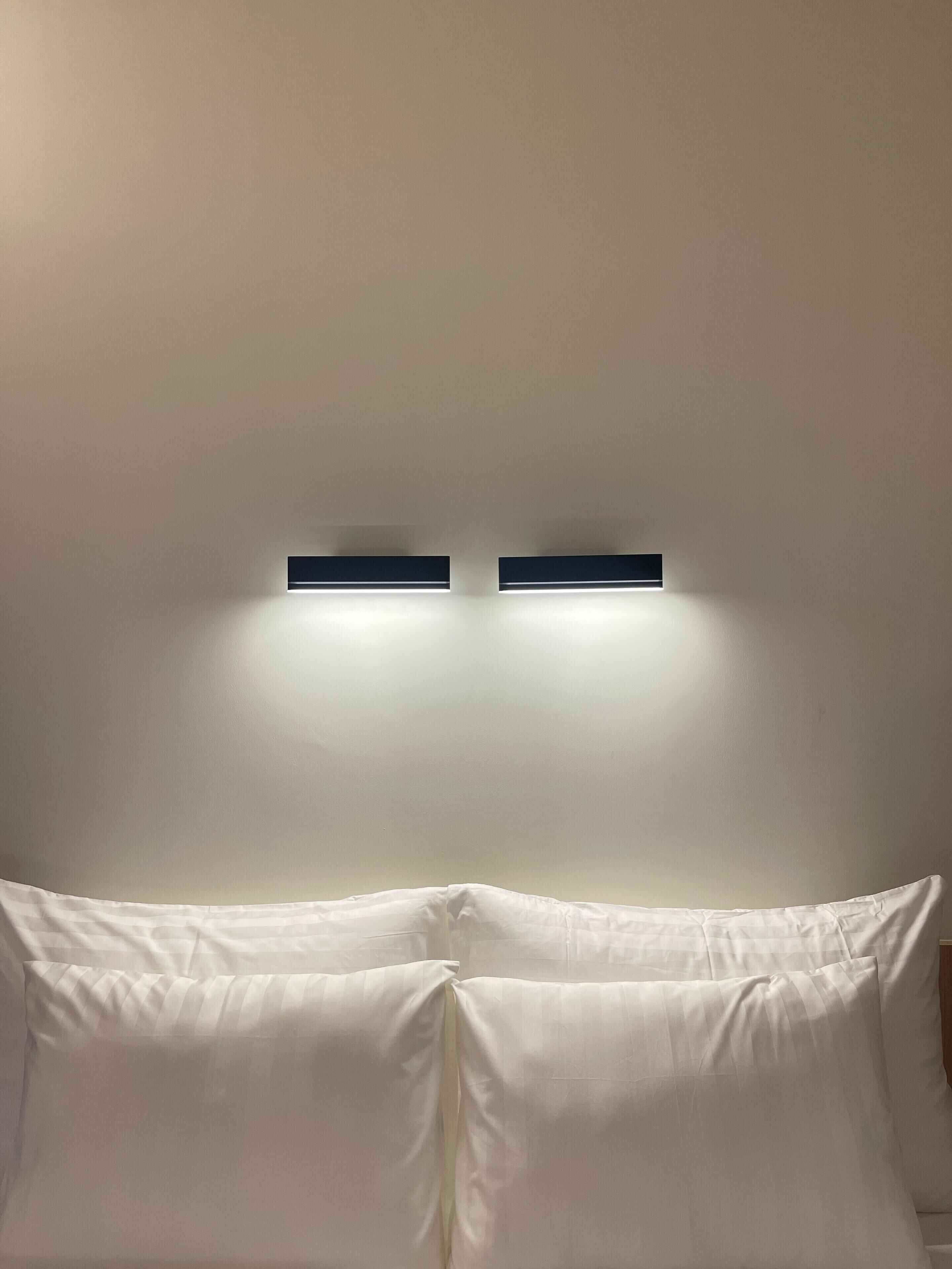 A room with a bed, two wall-mounted light fixtures, and a plain ceiling.