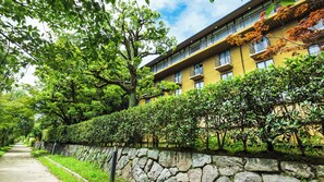 A multi-story building with a stone wall and lush greenery. - Daiyamonndo kyoto sosaethi  (Kyoto)