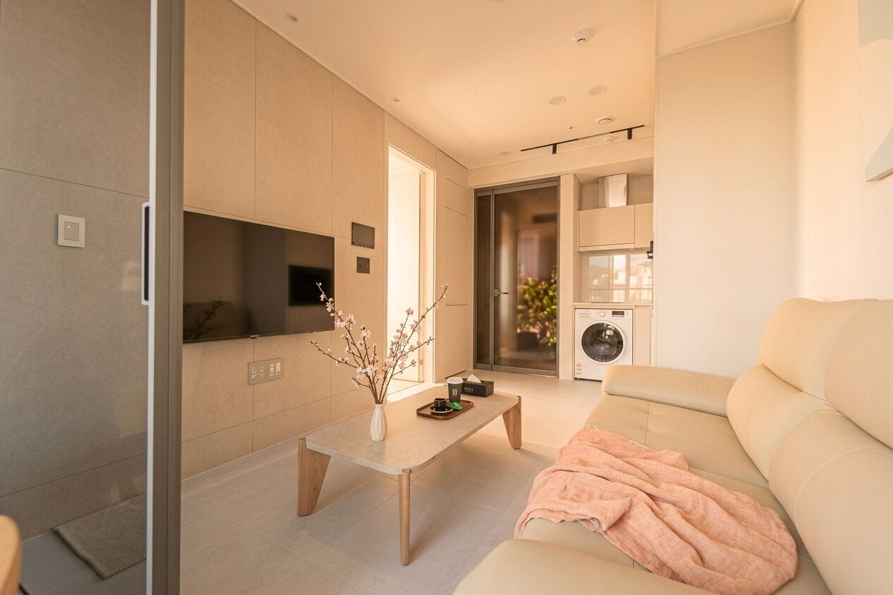 Una sala moderna con un sofá, una mesa de centro, un televisor y una lavadora.