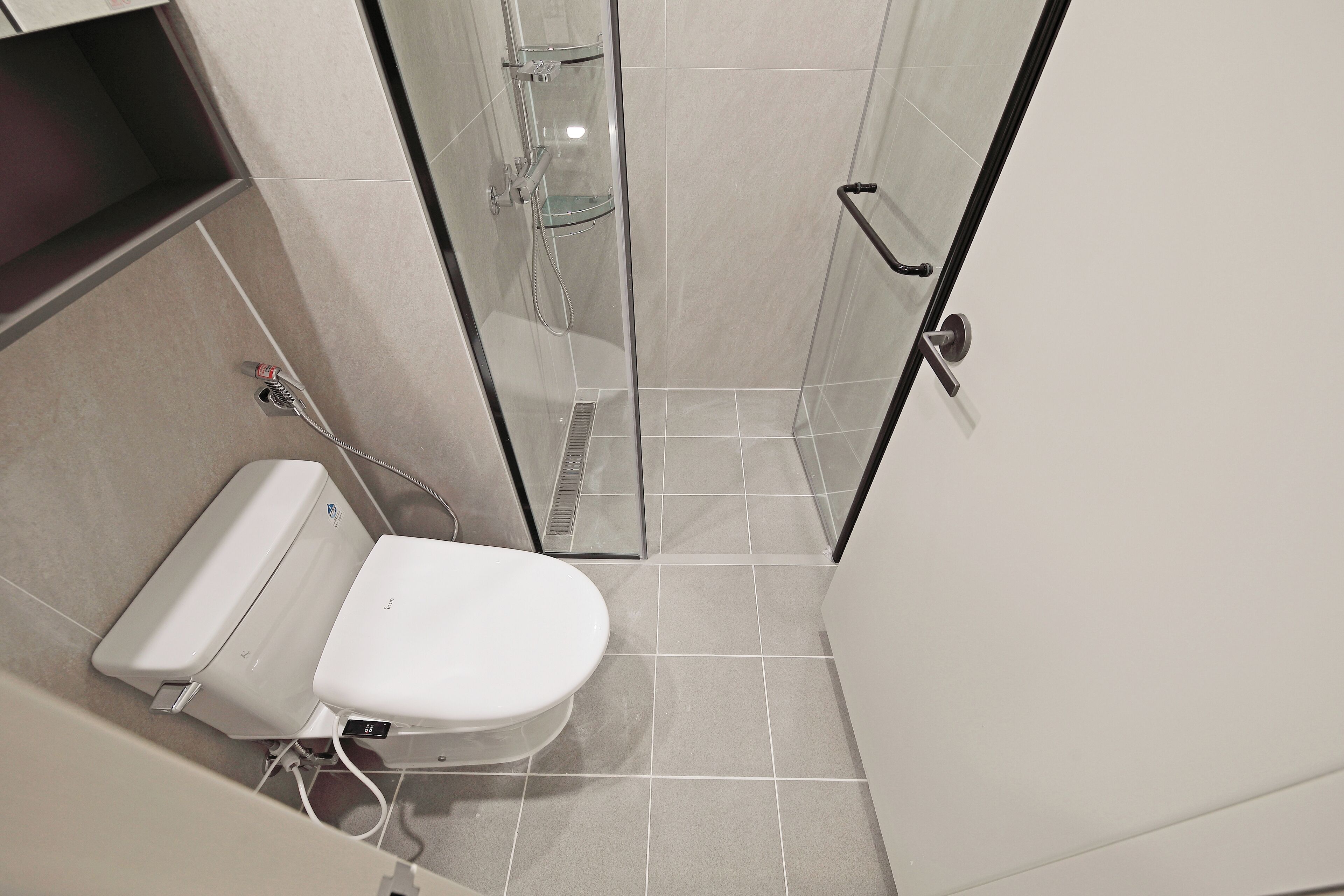 Un baño moderno con inodoro, ducha y cabina de ducha con paredes de vidrio.