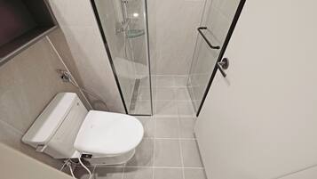 Un baño moderno con inodoro, ducha y cabina de ducha con paredes de vidrio.