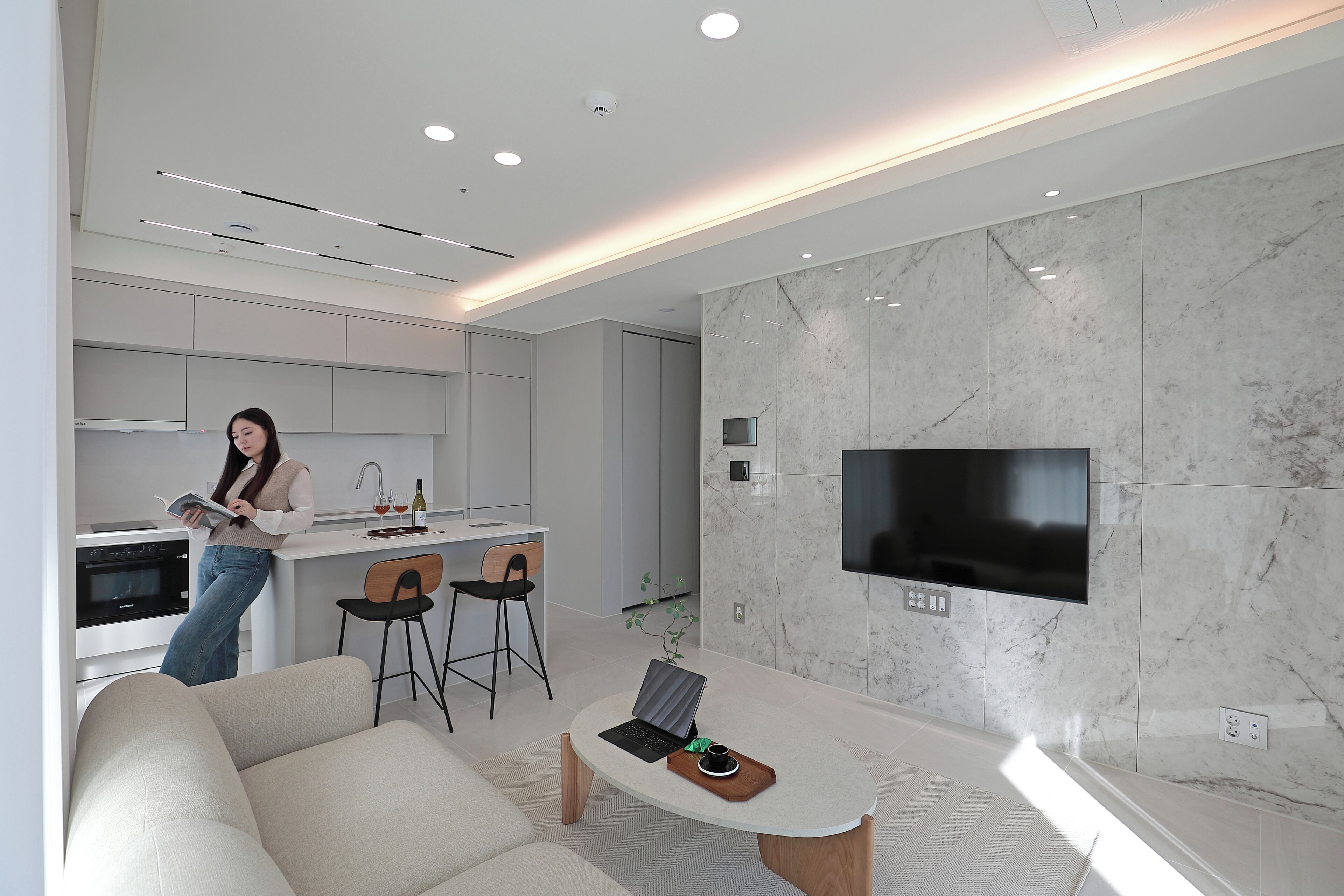 A modern living room with a sofa, a coffee table, and a TV mounted on the wall.