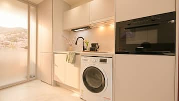 Cocina moderna con lavadora integrada, horno y vistas a flores de cerezo.
