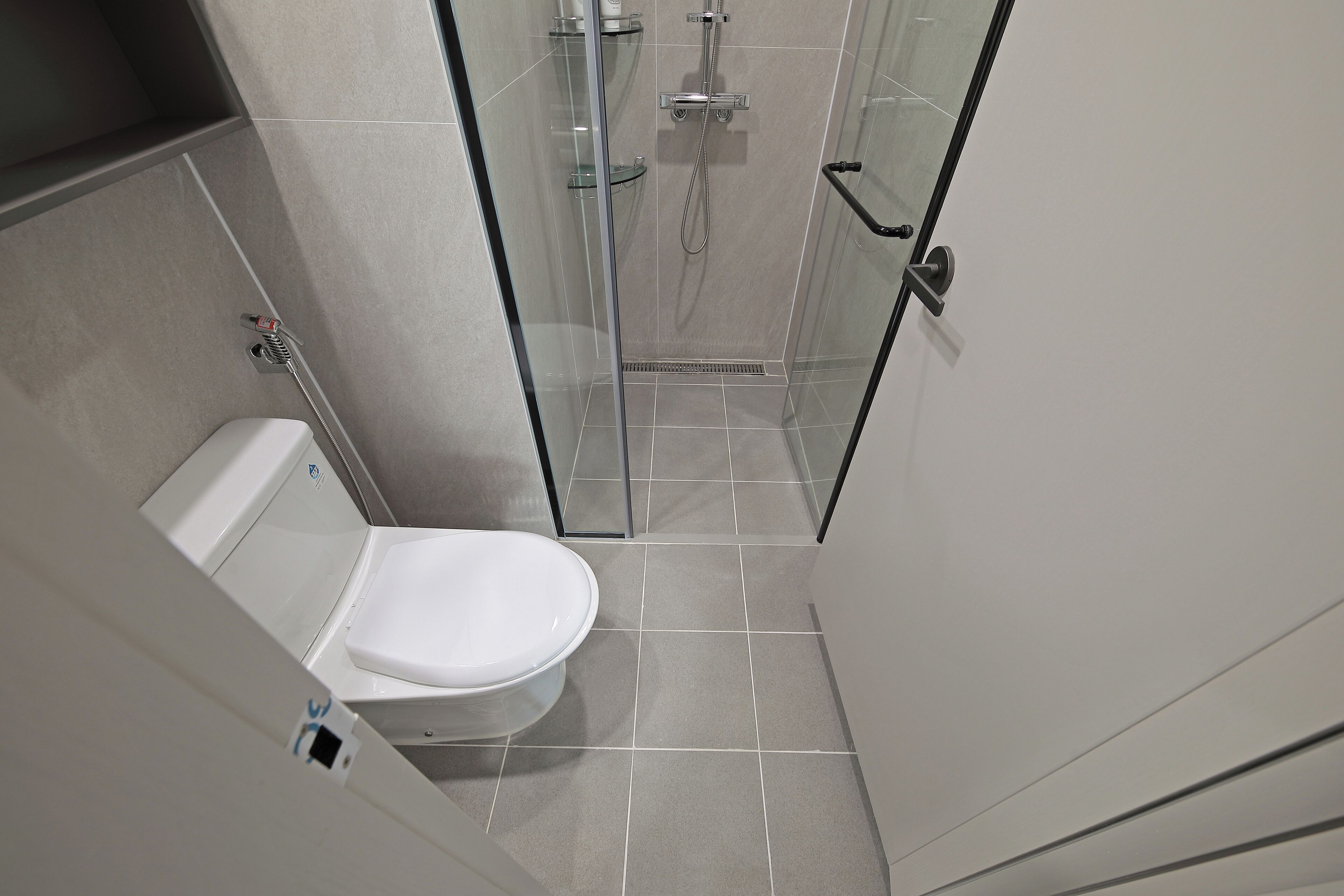 A modern bathroom with a toilet, a glass shower enclosure, and tiled flooring.