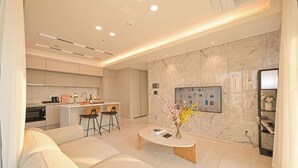 A modern living room with a sofa, coffee table, and kitchen area in the background. - SOTA SUITE Busan Seomyeon (Busan)