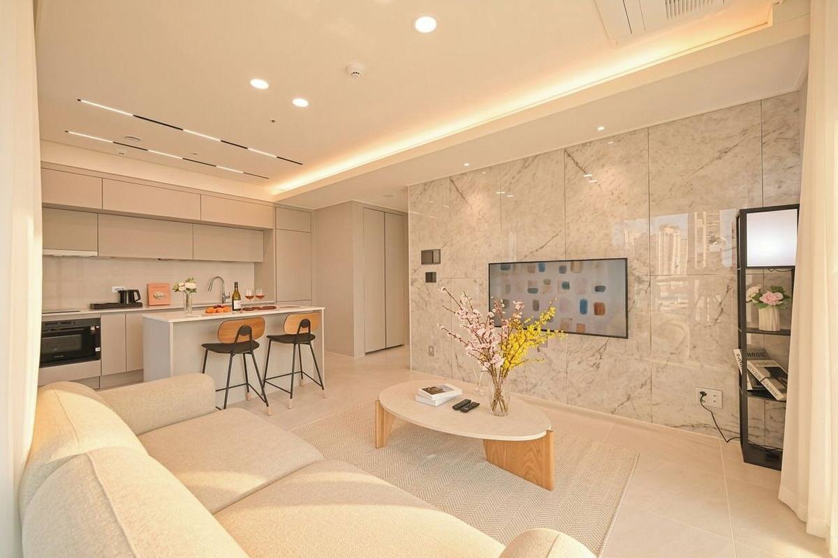 A modern living room with a sofa, coffee table, and kitchen area in the background.