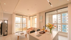 A modern living room with a sofa, coffee table, and a dining area with a glass top table. - SOTA SUITE Busan Seomyeon (Busan)