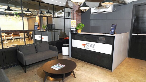 A reception area with a sofa, a coffee table, and a reception desk with a sign reading "mySTAY HOTEL". - mySTAY BGC West (Makati)
