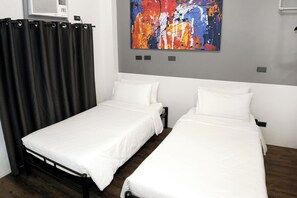 A room with two single beds, a large abstract painting on the wall, and a black curtain. - mySTAY BGC West (Makati)