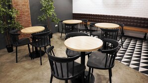A restaurant interior with round tables and black chairs, brick walls, and a black and white checkered floor. - mySTAY BGC West (Makati)