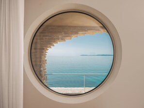 Une fenêtre ronde offrant une vue sur la mer et sur une terre lointaine.