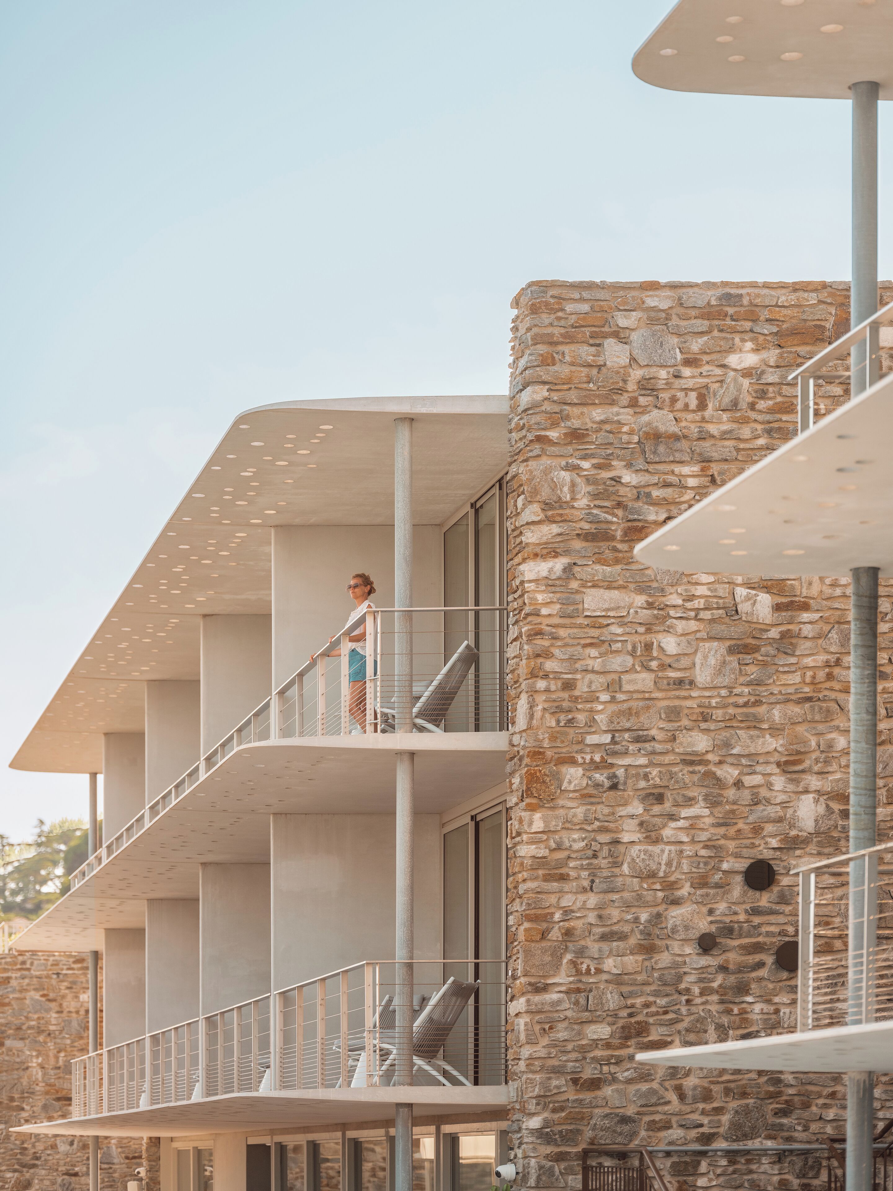 Un bâtiment moderne doté de nombreux balcons et d’une façade en pierre.