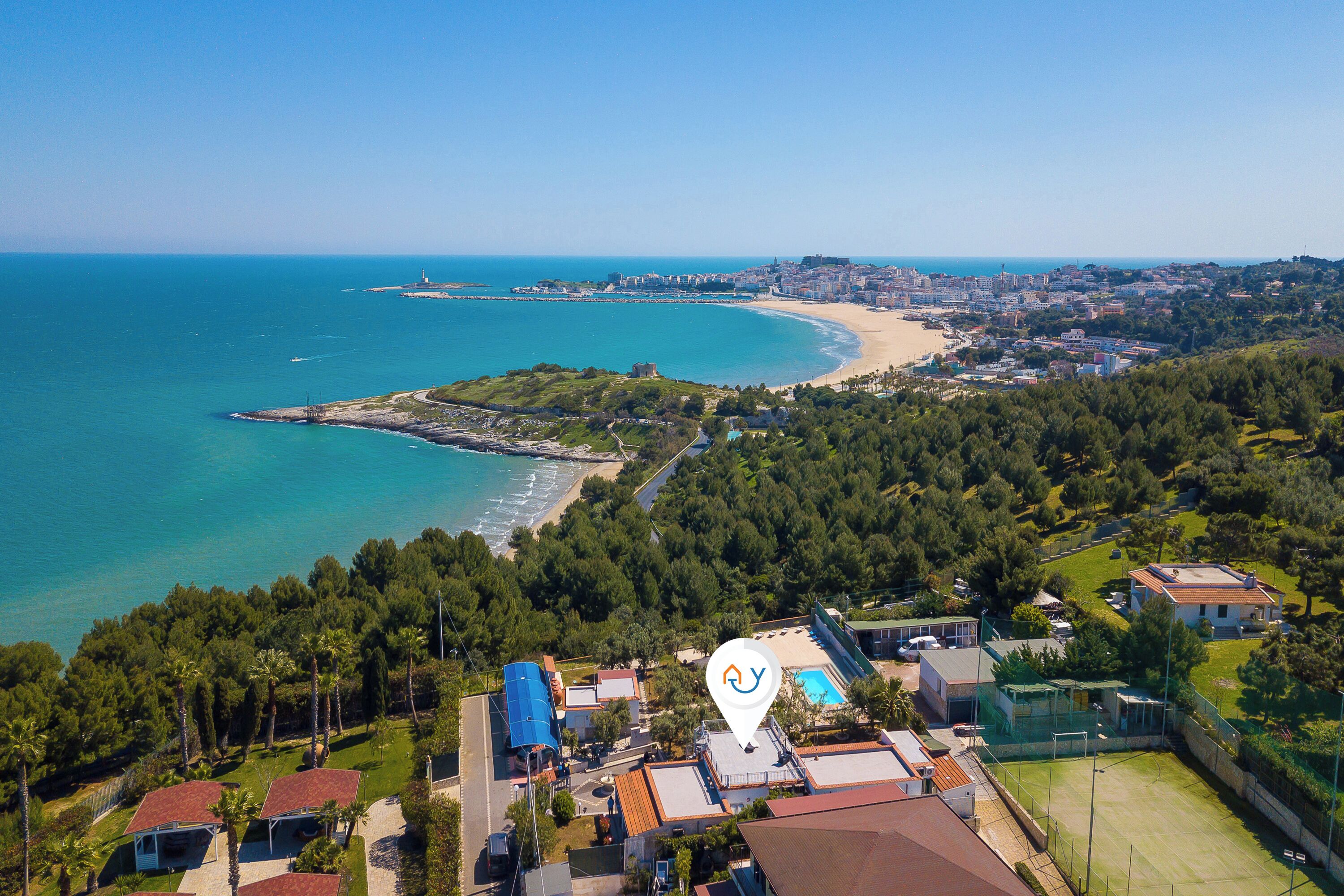 Vue aérienne d’une ville côtière avec une plage, un phare et un terrain de golf.