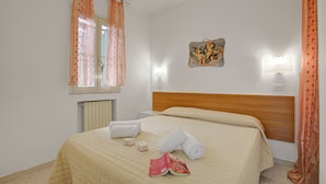 A hotel room with a bed, towels, a wall clock, and a painting. - Stella Marina Apartment 2 (Vieste)