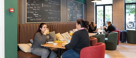 Un restaurante con cabinas y mesas, un menú en una pizarra y ventanas grandes.