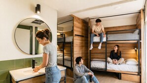 Un dormitorio con literas, un espejo redondo, un lavabo y suelo de madera.