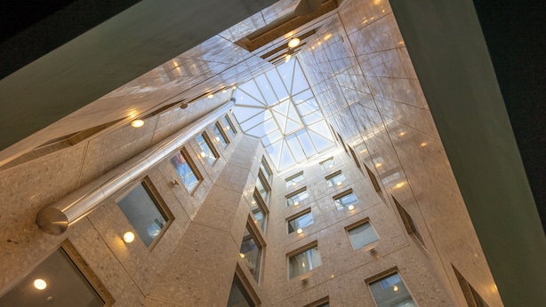 Un edificio de gran altura con techo de vidrio, varios pisos e iluminación interior.