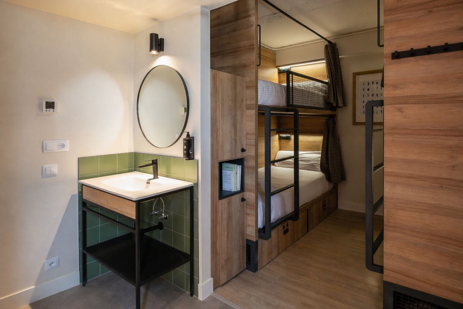 A compact room with a sink, mirror, and bunk beds.