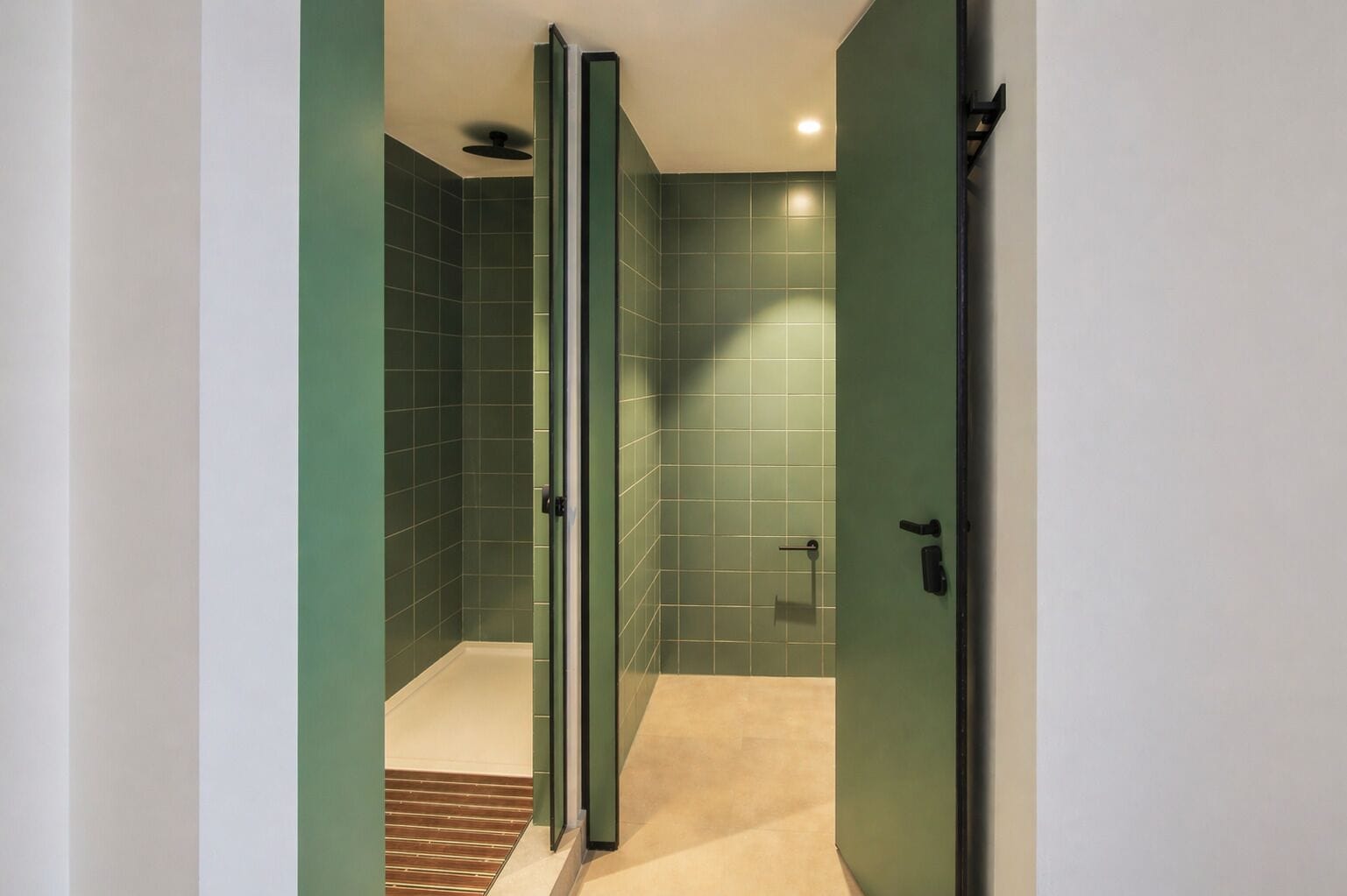 Een moderne badkamer met groene tegels, een douchecabine van glas en een beigekleurige vloer.