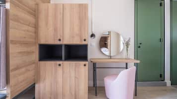 Une pièce avec une armoire en bois, un miroir, une porte verte et une chaise rose.