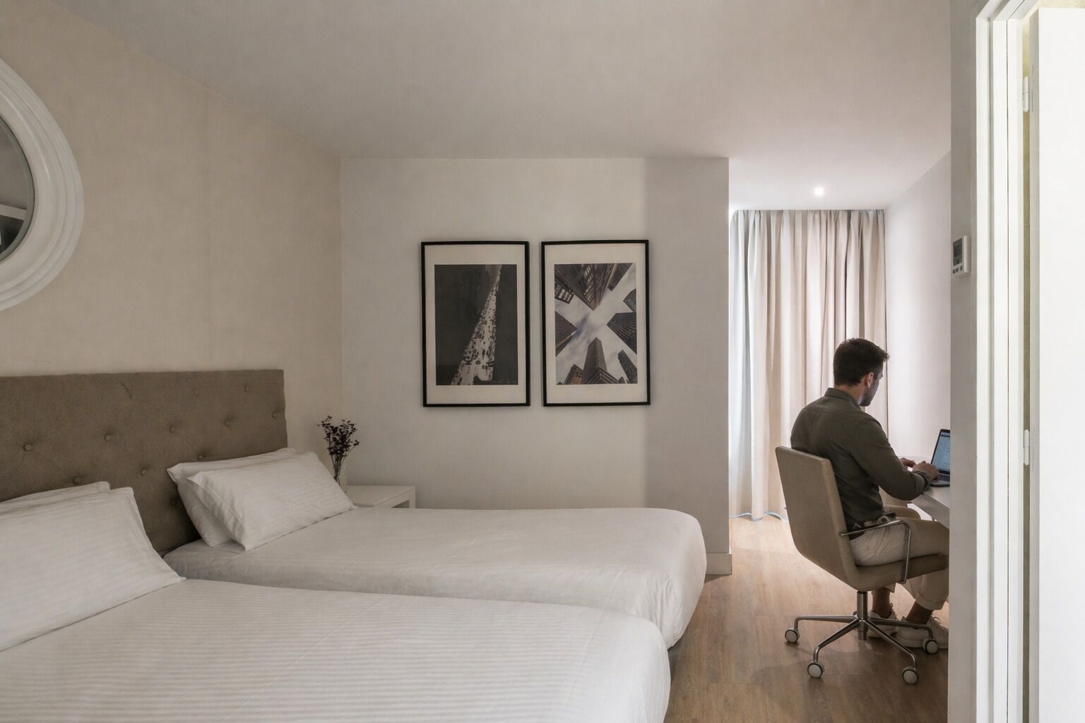 Habitación de hotel con dos camas, un escritorio y dos cuadros en la pared.