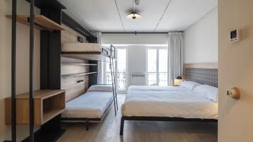 A bedroom with a large bed, a smaller bed, a wardrobe, and a desk.