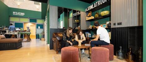 A modern interior with seating areas, a kitchen, and a sign reading "M'EATING".