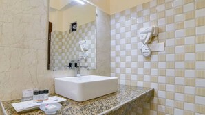 A bathroom with a white sink, a hairdryer mounted on the wall, and toiletries on the counter. - Orsino Khangri Karpo Retreat & SPA (Lachung)