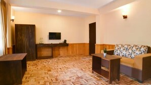 A hotel lobby with a wooden reception desk, a sofa with a fruit pattern, and a herringbone-patterned floor. - Orsino Khangri Karpo Retreat & SPA (Lachung)