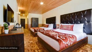 A family room with a balcony, wooden flooring, two beds with red and white bedding, a flat-screen TV, and a potted plant. - Orsino Khangri Karpo Retreat & SPA (Lachung)