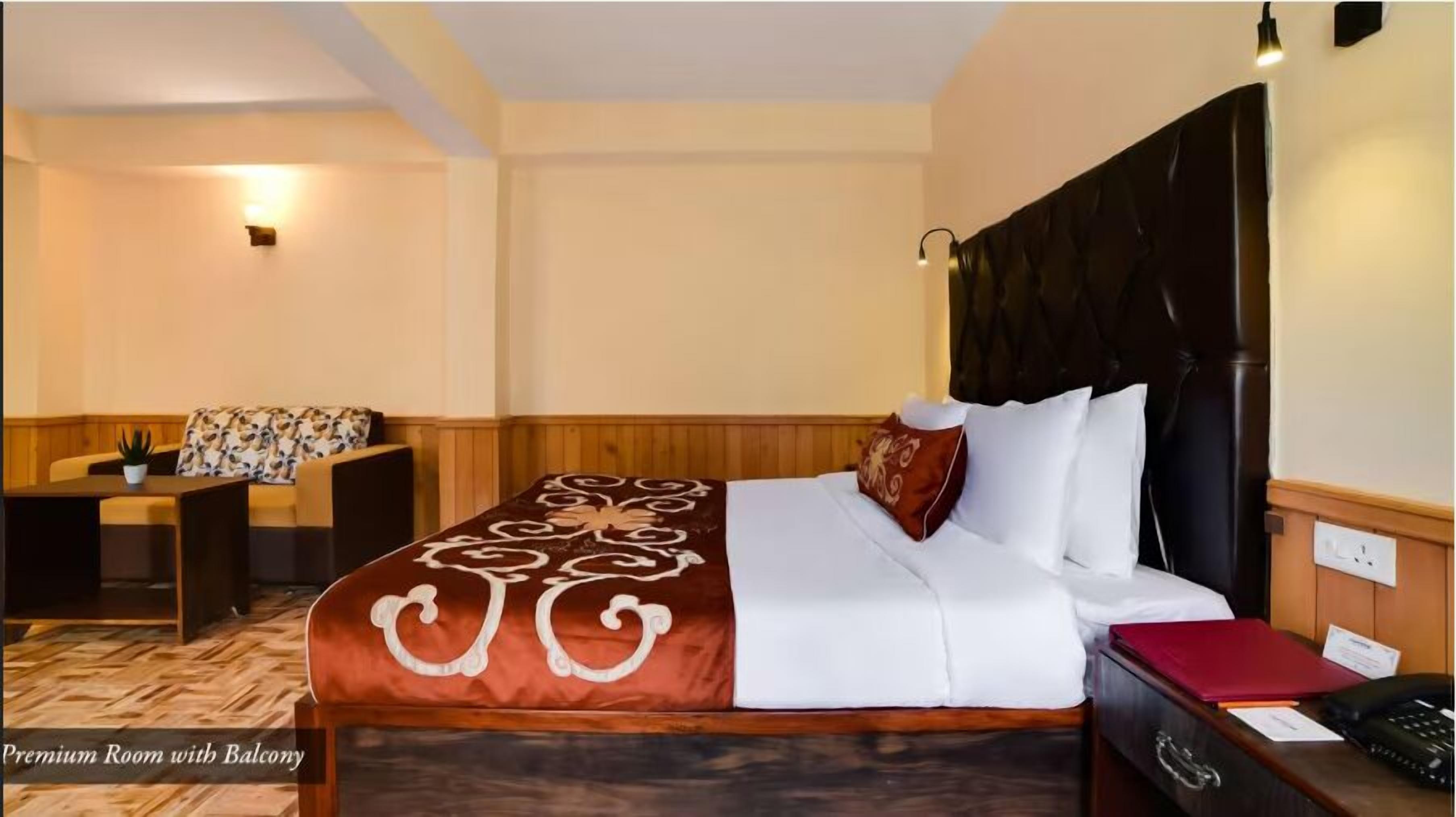 A hotel room with a bed, a desk, a chair, and a small table.