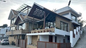 A modern two-story house with a flat roof, large windows, and a balcony. - RS Family Stay  (Kodaikanal)