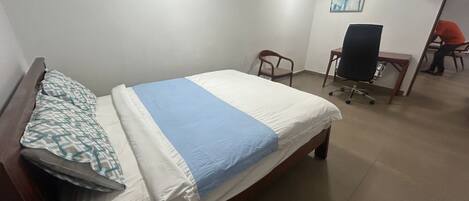 Una habitación de hotel con una cama, un escritorio y una silla.