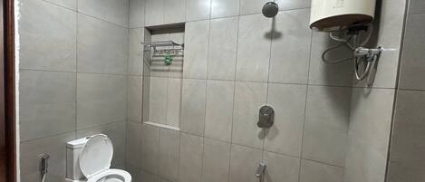 Pieni kylpyhuone, jossa on wc, suihku ja punainen ämpäri.